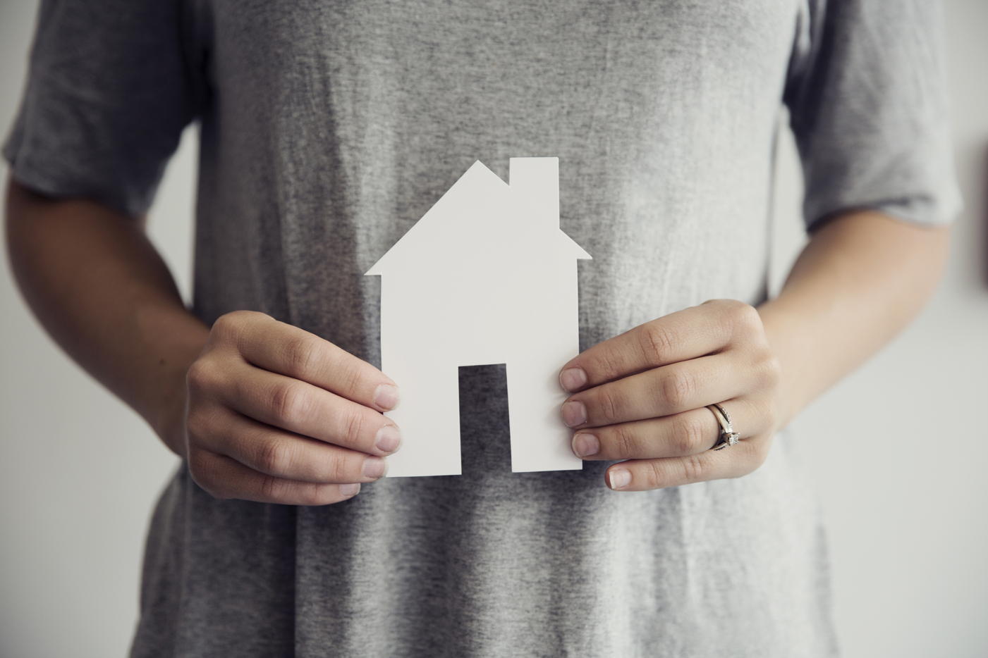 Hands holding a paper cut out of a house