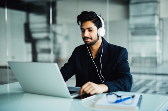 Man wearing headphones looking at a laptop