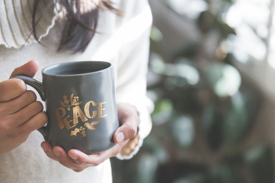 Someone holding a coffee cup with the word 'peace' on it