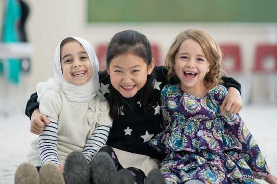 Three girls of different faith and ethnicity sharing a hug