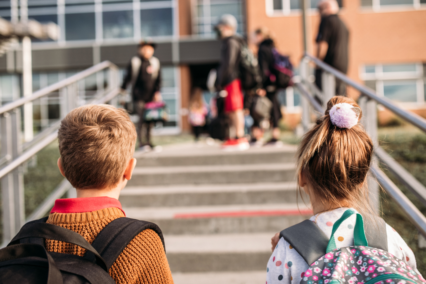 A young boy and young girl walking into school