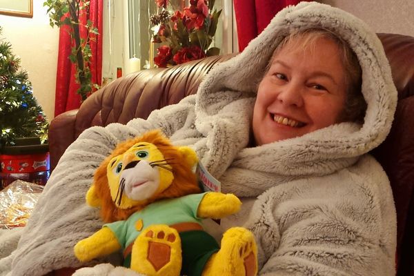 A smiling woman holding a soft toy lion