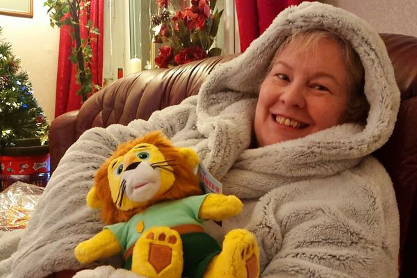 A smiling woman holding a soft toy lion