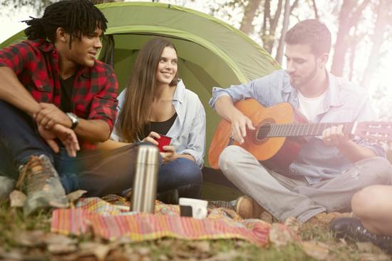 Three young people singing in front of a tent